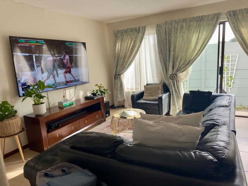 A comfortable living room featuring tiled flooring and a large sliding glass door that provides access to the outdoor area.