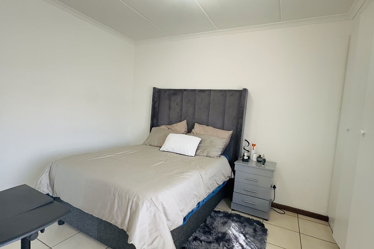 A functional bedroom featuring tiled flooring and a built-in wardrobe, offering a clean and neutral space ready for personalization.