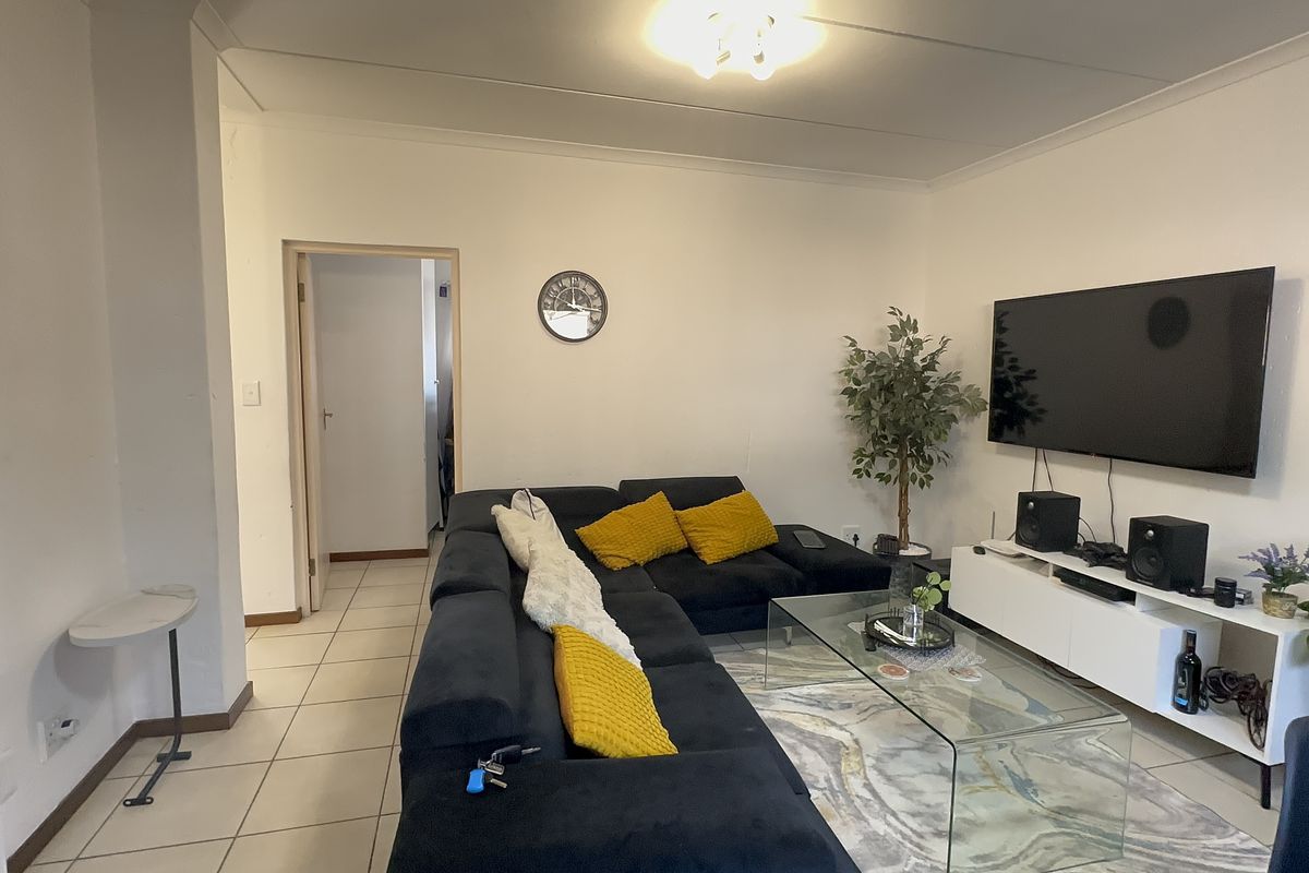 A functional living room featuring tiled flooring and neutral wall finishes, providing a comfortable and well-lit space for relaxation.