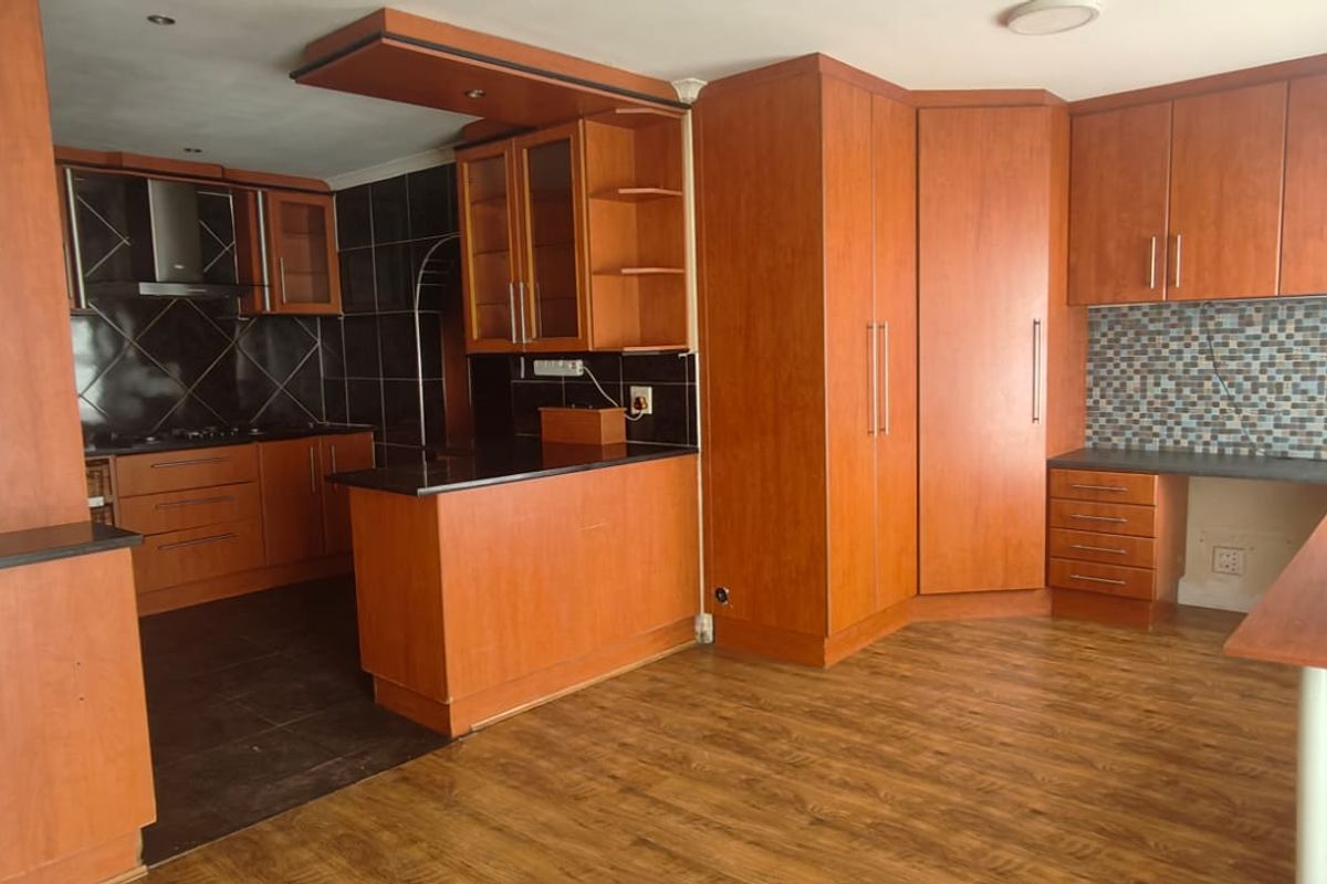 Spacious kitchen featuring extensive wood-finish cabinetry, integrated desk area, mosaic tile backsplash, and durable laminate flooring.