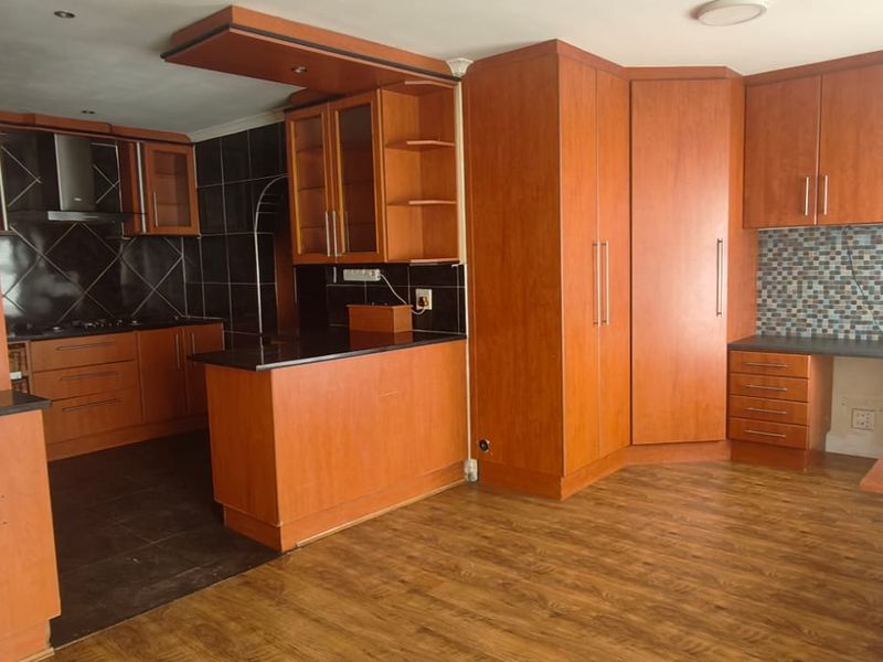 Spacious kitchen featuring extensive wood-finish cabinetry, integrated desk area, mosaic tile backsplash, and durable laminate flooring.