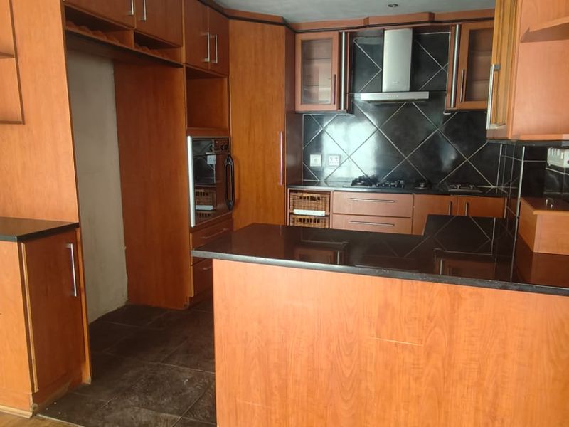 A functional kitchen featuring wood-tone cabinetry, black granite countertops, a built-in oven, and a tiled backsplash, offering a solid foundation for modernization.