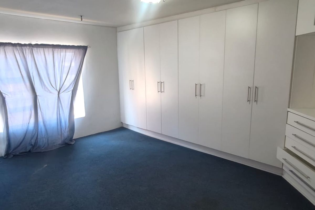 A spacious bedroom featuring extensive floor-to-ceiling built-in cupboards and integrated drawer storage, providing ample organizational space.