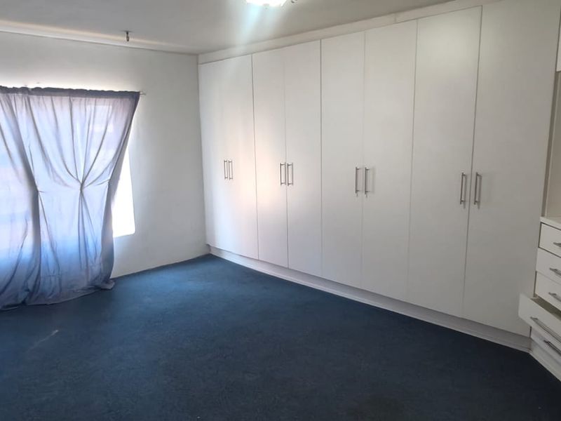 A spacious bedroom featuring extensive floor-to-ceiling built-in cupboards and integrated drawer storage, providing ample organizational space.