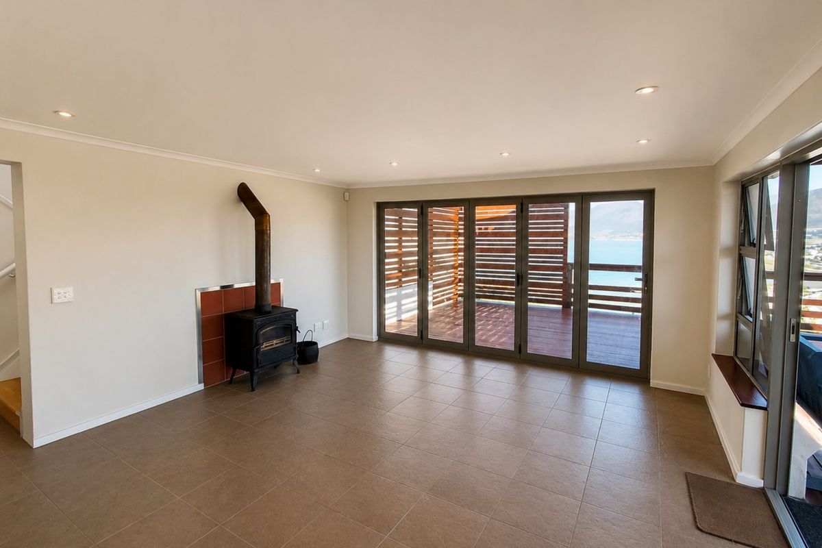 Spacious living area featuring tiled floors, a freestanding fireplace, and large bi-fold doors opening onto a deck with scenic views.