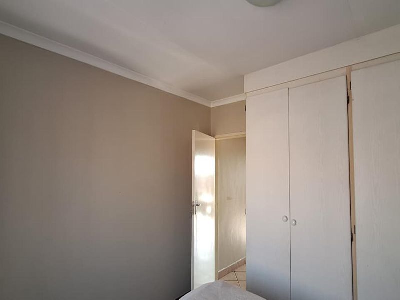 A clean, empty bedroom featuring neutral wall tones, white built-in cupboards, and coving detail, offering a blank canvas for personalization.