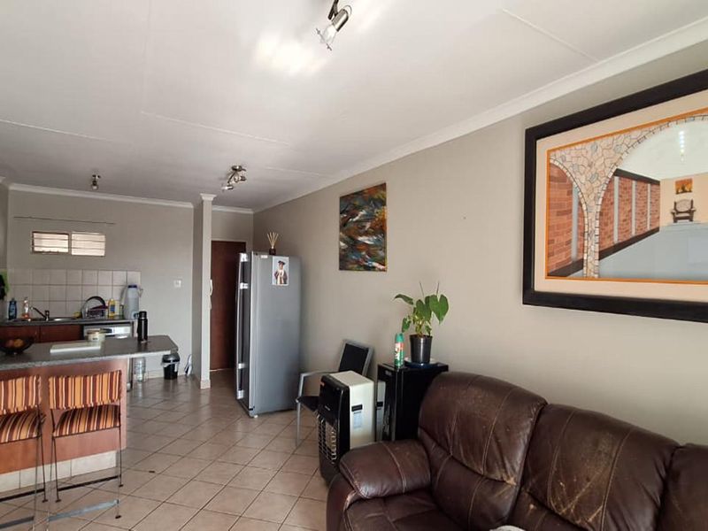 Open plan living area featuring a functional kitchen with breakfast bar, tiled flooring, and neutral wall finishes, suitable for modern updates.
