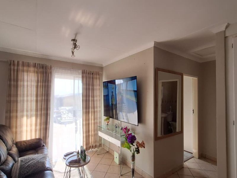 A living room featuring tiled flooring, coved ceilings, and a sliding glass door providing access to the exterior.