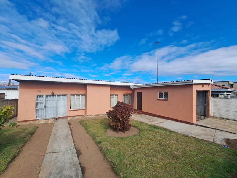 Rear view of a single-story house featuring a concrete walkway, paved driveway, and security gates on the doors and windows.