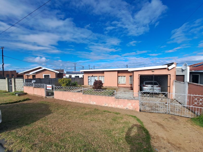Front exterior view of a single-story house featuring a perimeter wall, metal security gate, and an attached garage.