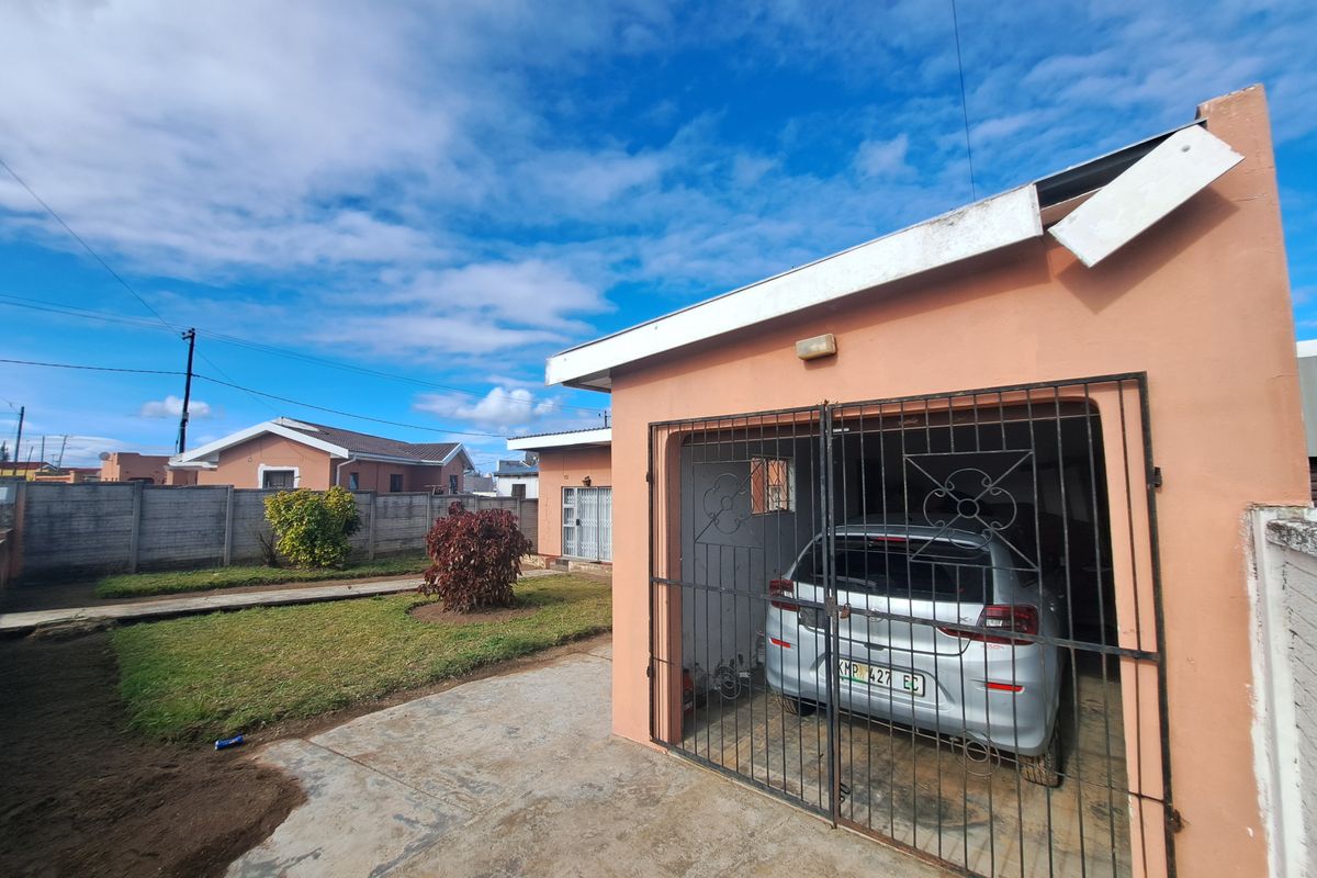Front view of the property featuring a single garage with a metal security gate, concrete driveway, and a precast boundary wall.
