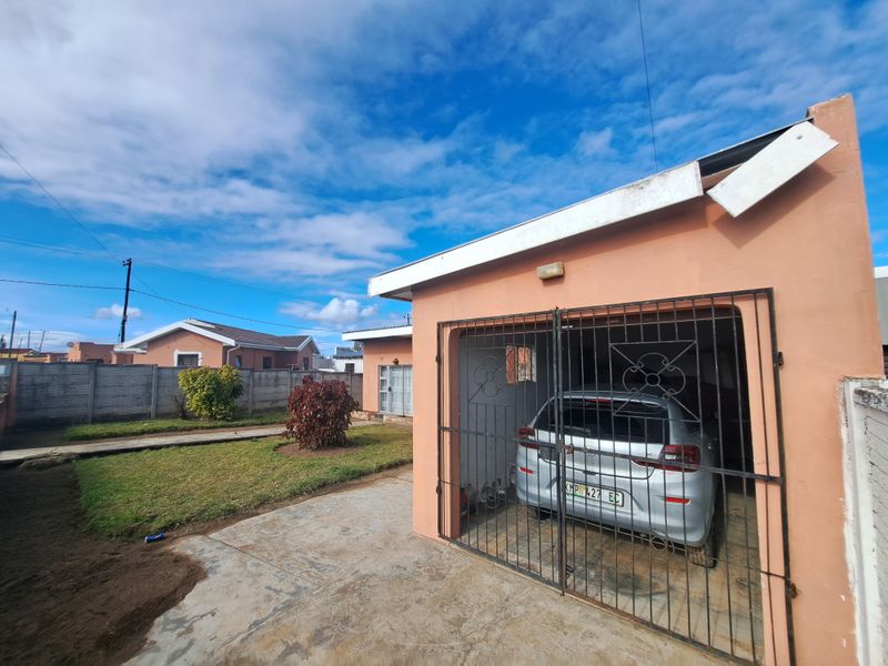 Front view of the property featuring a single garage with a metal security gate, concrete driveway, and a precast boundary wall.