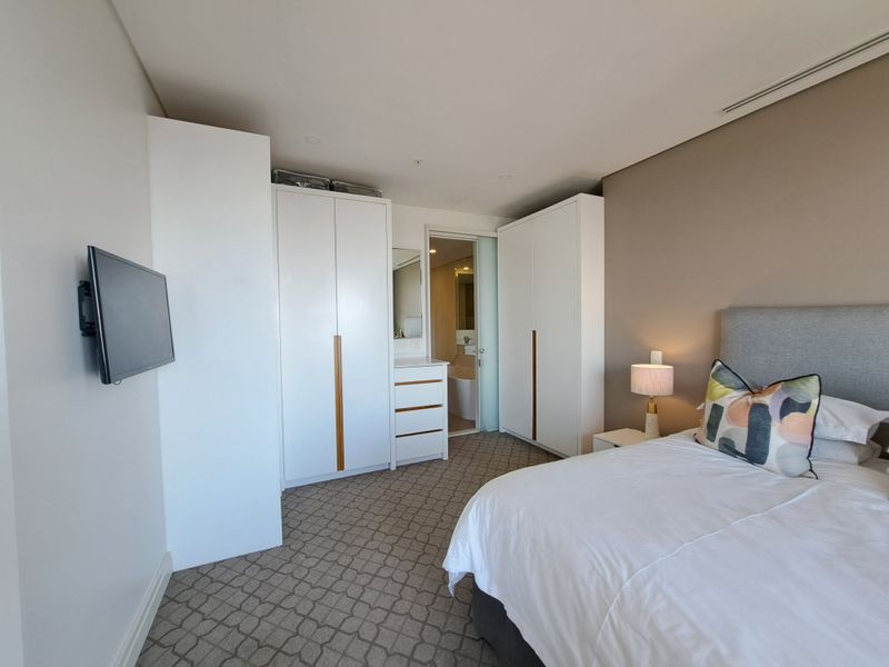 A well-maintained bedroom featuring built-in wardrobes, integrated vanity, carpeted flooring, and direct access to an en-suite bathroom.