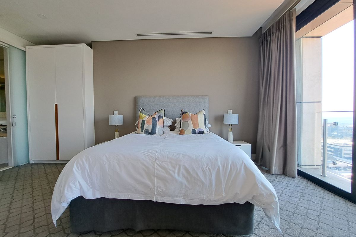 A well-maintained bedroom featuring built-in cabinetry, recessed ceiling lighting, and large glass sliding doors providing natural light and access to an outdoor area.