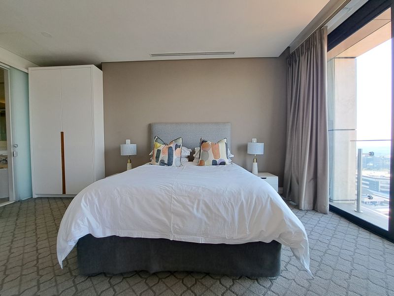 A well-maintained bedroom featuring built-in cabinetry, recessed ceiling lighting, and large glass sliding doors providing natural light and access to an outdoor area.
