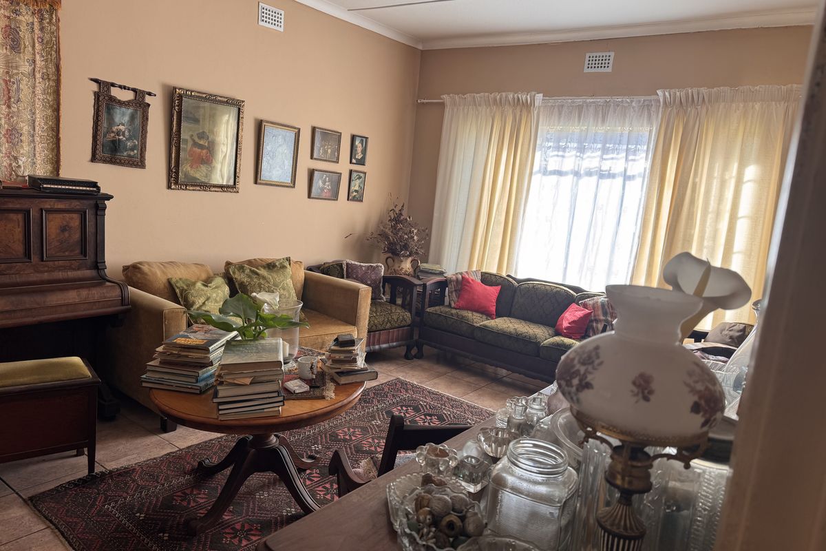 A spacious living room featuring tiled flooring and natural light through large windows, offering a comfortable and traditional living space.