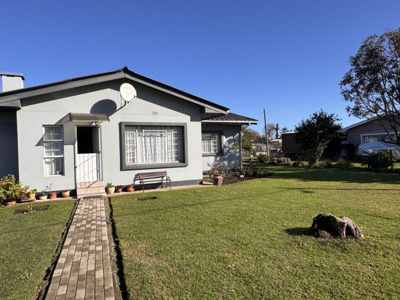 Front view of a single-story house featuring a paved walkway, well-maintained lawn, and exterior security features.