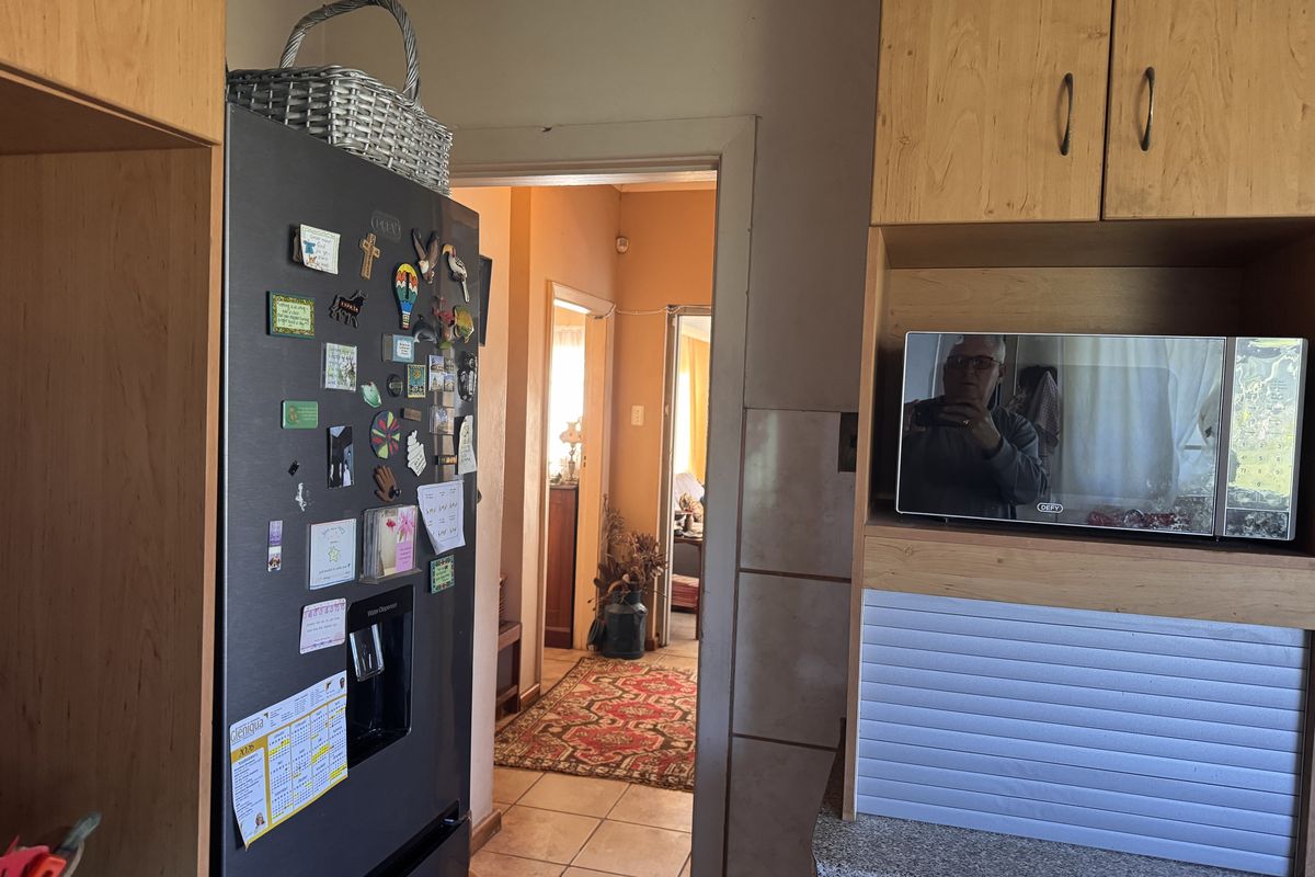 A functional kitchen area featuring built-in cabinetry, laminate countertops, and a dedicated microwave shelf, with a view leading into the adjacent living space.