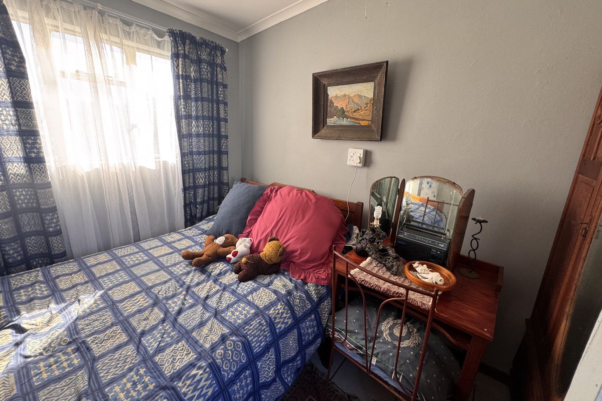 A functional bedroom featuring neutral wall finishes, cove cornicing, and a window with natural light exposure.