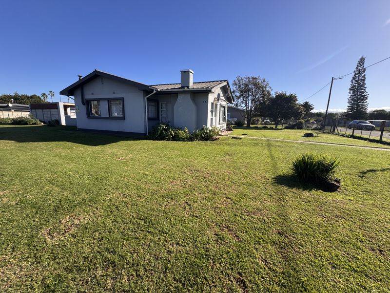 A detached single-story house featuring a metal roof, chimney, and a spacious surrounding lawn area.
