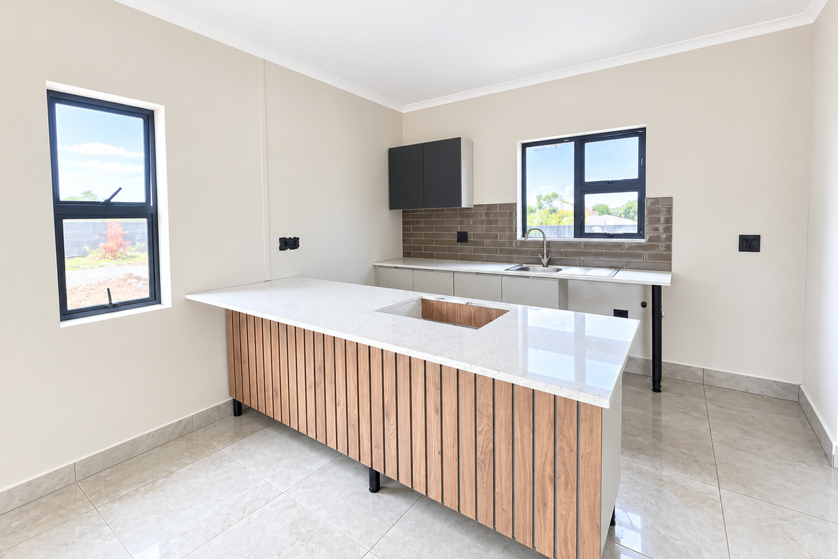 Modern, empty kitchen featuring a central island with a quartz countertop, sleek cabinetry, tiled backsplash, and large windows providing ample natural light.