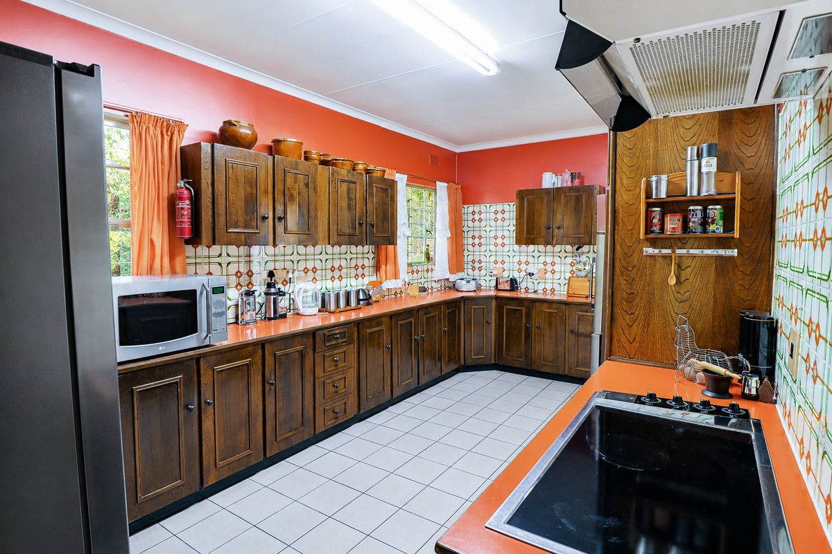 A spacious kitchen featuring traditional wooden cabinetry, patterned tile backsplash, and ceramic flooring, offering a functional layout with integrated cooking appliances.