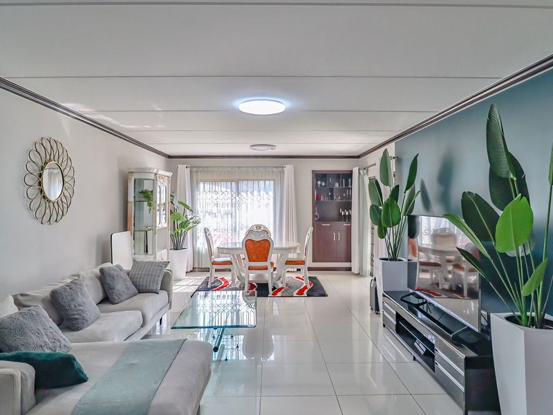 Spacious open-plan living and dining area featuring polished tiled flooring, a built-in display cabinet, and large sliding glass doors providing natural light.