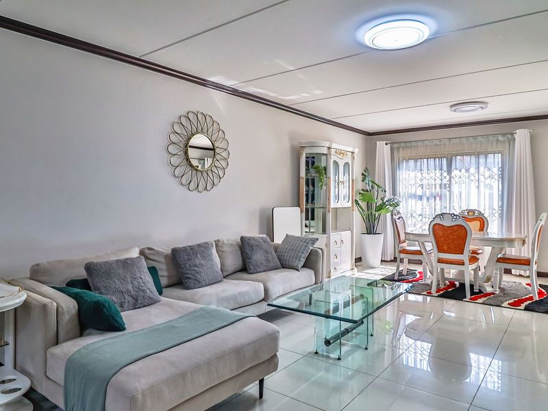 Spacious open-plan living and dining area featuring polished tiled flooring, modern ceiling lighting, and large sliding glass doors leading to the exterior.