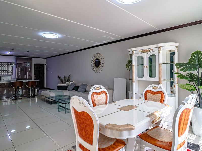 Spacious open-plan living and dining area featuring modern tiled flooring, recessed lighting, and a well-integrated kitchen with a breakfast island.