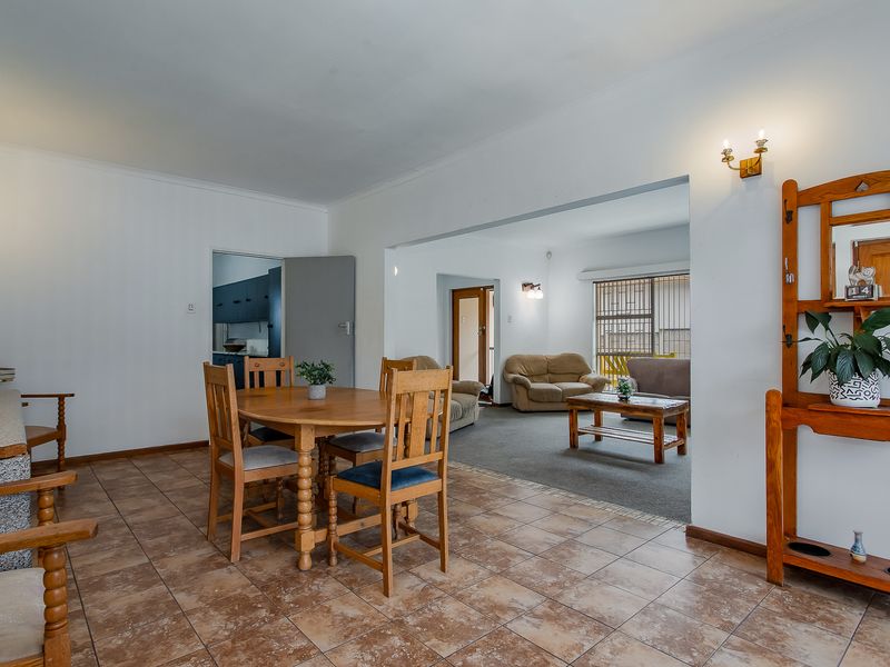 Open-plan living and dining area featuring a mix of tiled and carpeted flooring, with direct access to a secondary kitchen space.