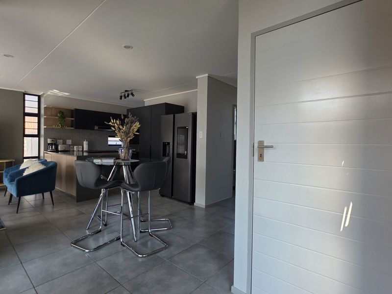 Modern open-plan living area featuring tiled floors, a contemporary kitchen with island, and neutral finishes, creating a seamless flow between kitchen and living spaces.