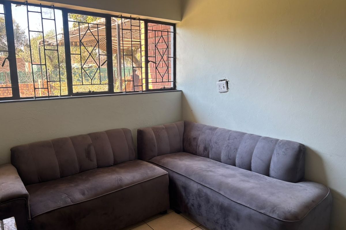 A living area featuring tiled flooring and security bars on the windows, with an exposed electrical connection point requiring a faceplate.