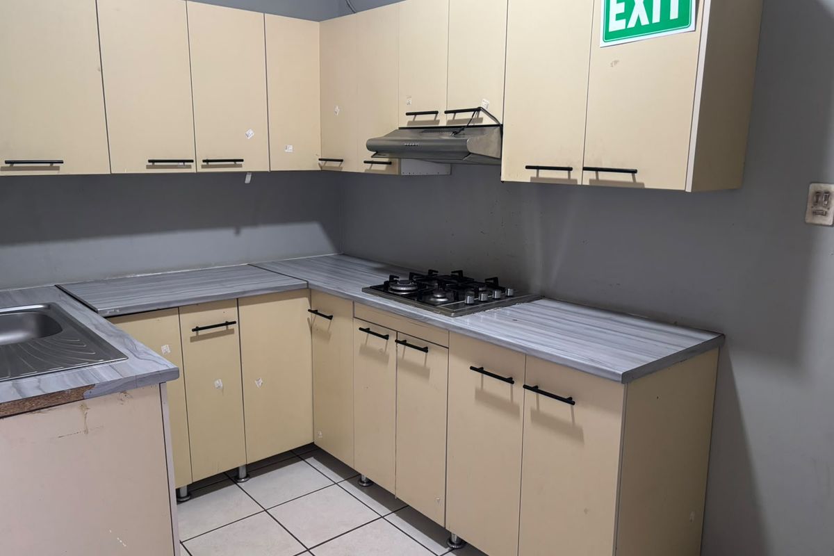 A functional kitchen featuring laminate countertops, built-in cabinetry, a gas hob, and an extractor fan, requiring cosmetic updates to improve its overall aesthetic appeal.