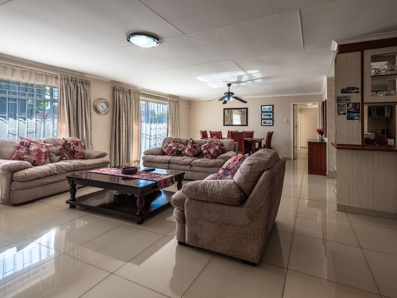 Spacious open-plan living and dining area featuring polished tile flooring, a ceiling fan, and integrated cabinetry, offering a functional and well-lit layout.