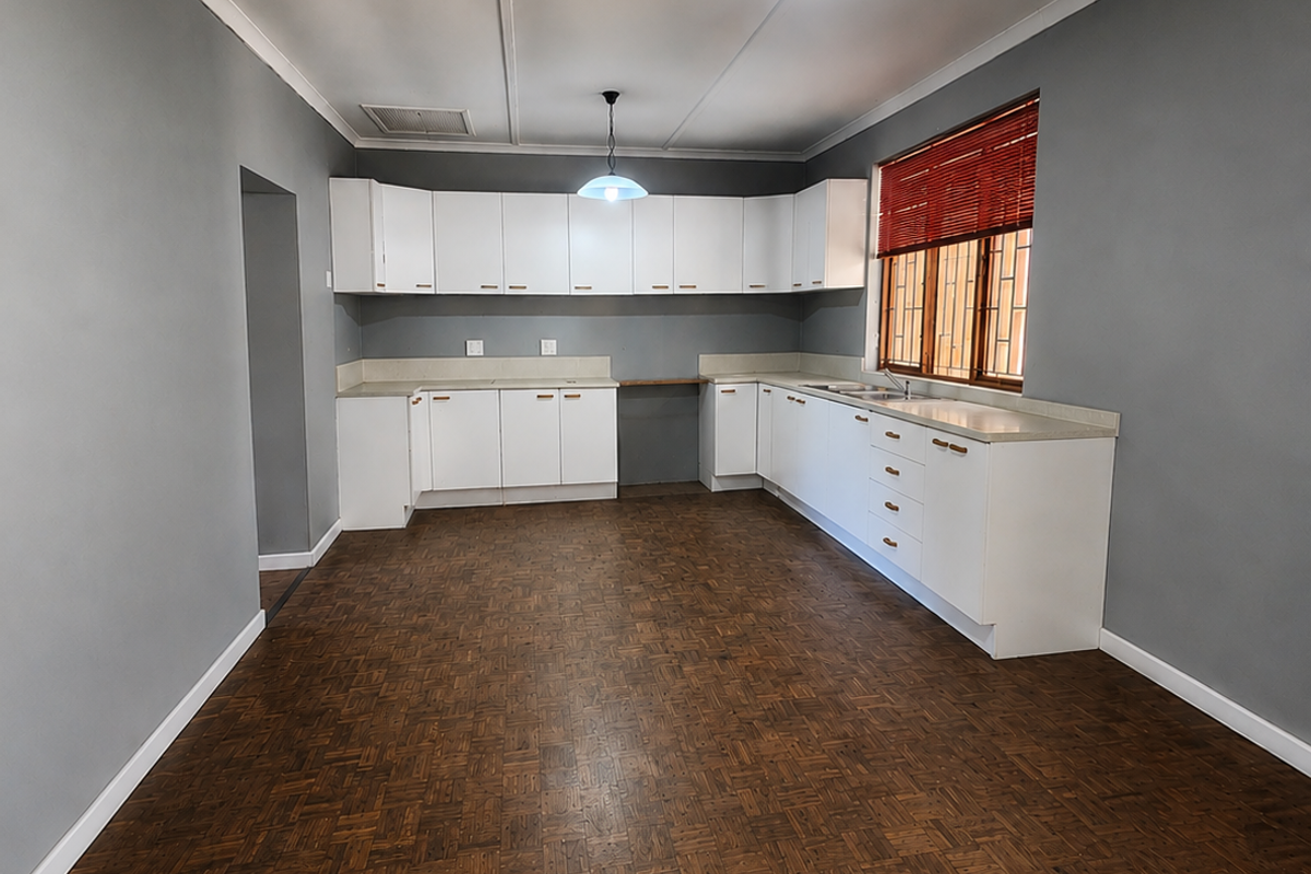 Spacious kitchen featuring white built-in cabinetry, laminate countertops, a double basin sink, and classic parquet flooring, offering a clean and functional layout.