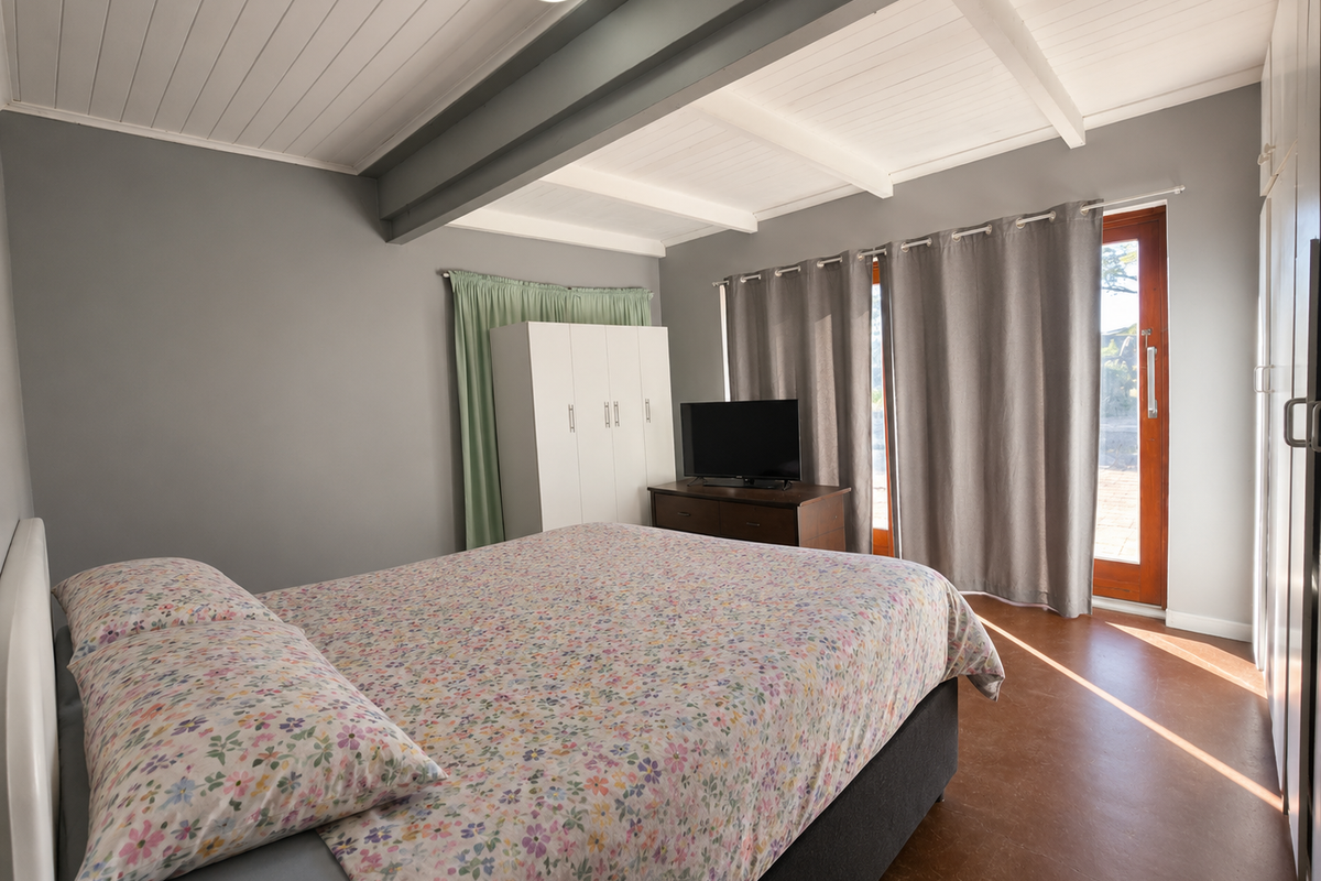 A bedroom featuring exposed ceiling beams, built-in wardrobe storage, and direct access to an outdoor area through a timber door.