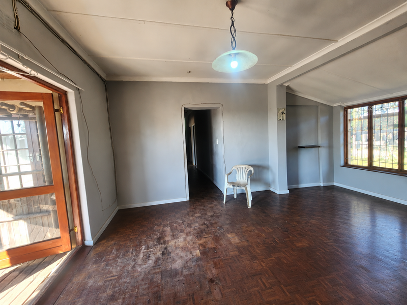 Spacious living area featuring original parquet flooring, timber-framed windows, and a glass-paneled door leading to the exterior.