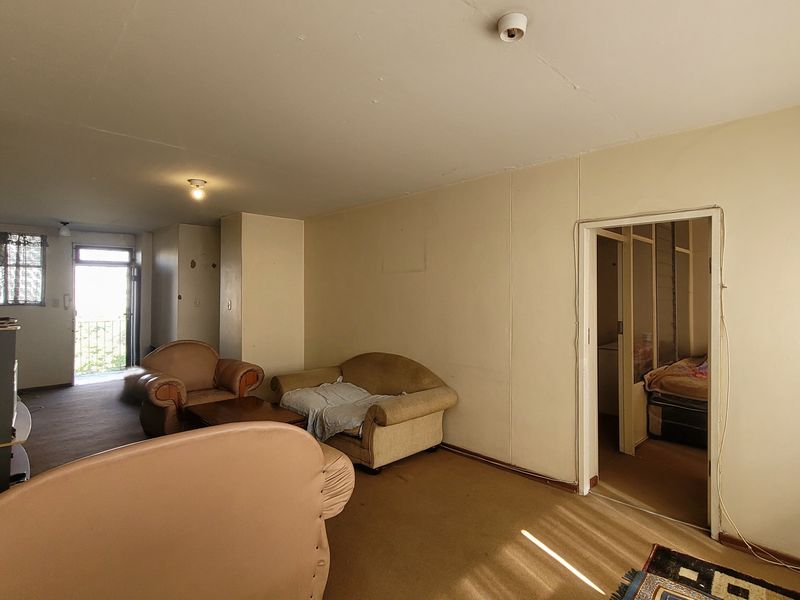 A living room area featuring carpet flooring and access to an external balcony, requiring cosmetic updates to improve the overall finish.