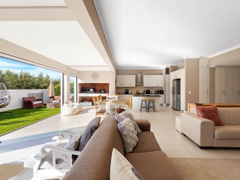 Spacious open-plan living and kitchen area featuring modern cabinetry, a central island, and seamless flow to an outdoor patio with a built-in fireplace.
