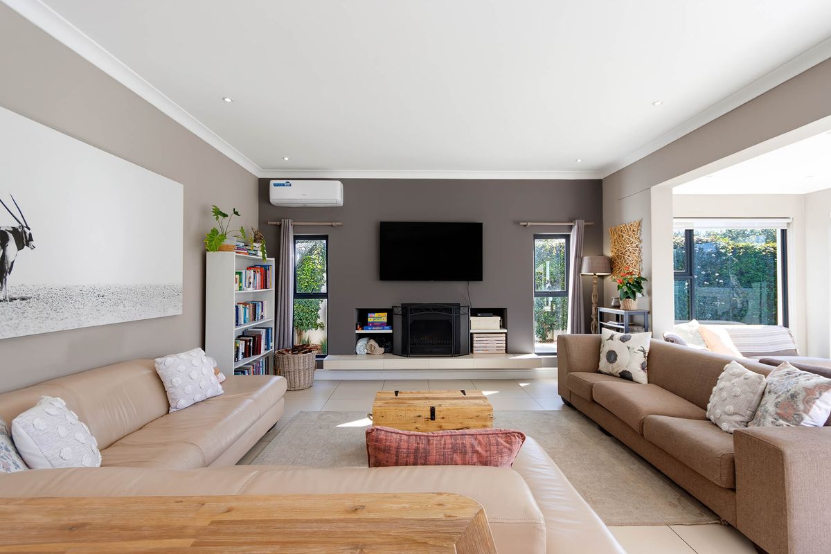 Spacious living room featuring a central fireplace, split-system air conditioning, and neutral tiled flooring with recessed lighting.
