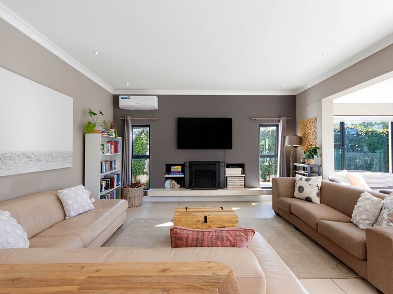 Spacious living room featuring a central fireplace, split-system air conditioning, and neutral tiled flooring with recessed lighting.