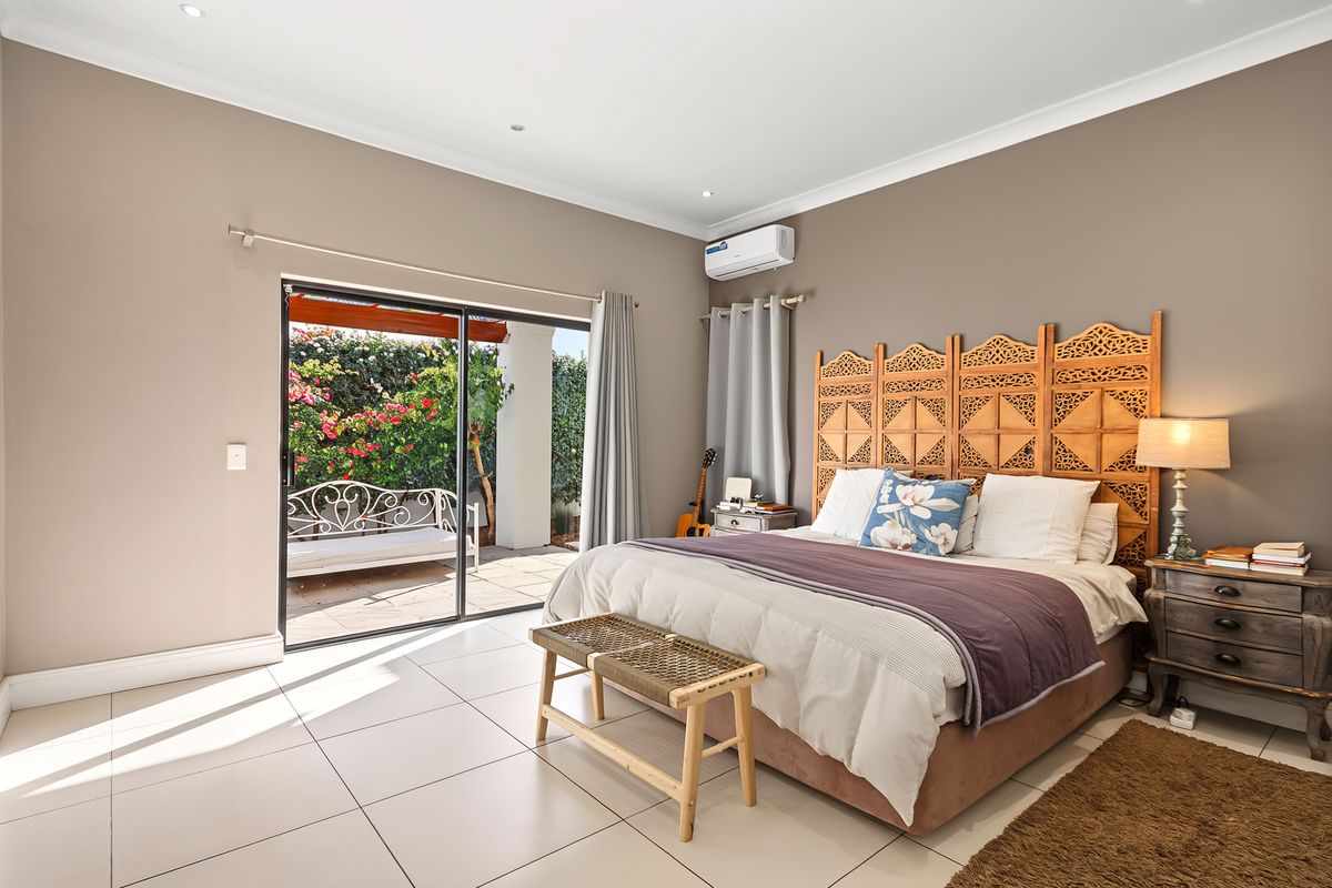Spacious bedroom featuring tiled flooring, recessed lighting, and a sliding glass door providing direct access to the outdoor patio area.