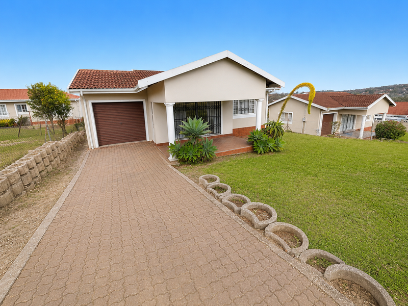 Front view of a townhouse featuring a paved driveway, single garage, and a covered entrance porch with security bars.