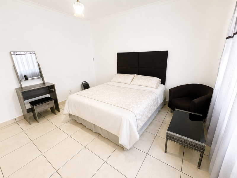 A well-maintained bedroom featuring neutral tiled flooring and clean white walls, providing a bright and functional living space.