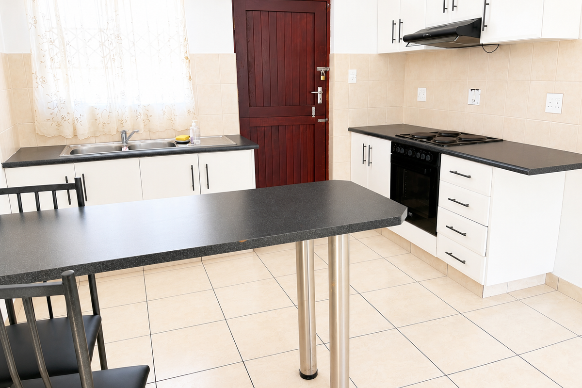 Functional kitchen featuring white cabinetry, dark laminate countertops, built-in oven and hob, tiled splashbacks, and a convenient breakfast bar area.