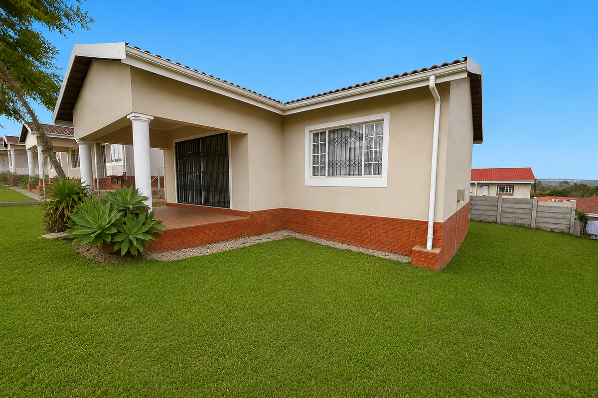 Rear view of a townhouse featuring a covered patio, brick plinth detailing, and a well-maintained lawn area.