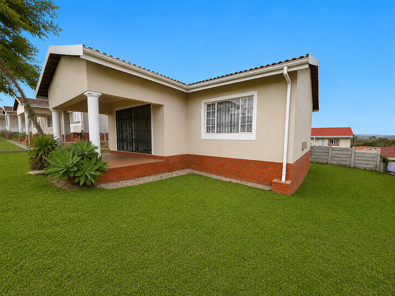 Rear view of a townhouse featuring a covered patio, brick plinth detailing, and a well-maintained lawn area.