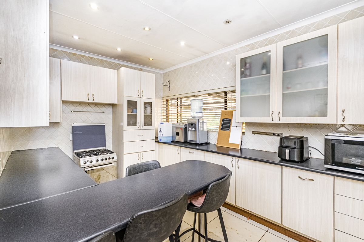 Functional kitchen featuring light-toned built-in cabinetry, dark laminate countertops, a gas stove, tiled backsplash, and a convenient breakfast bar area.