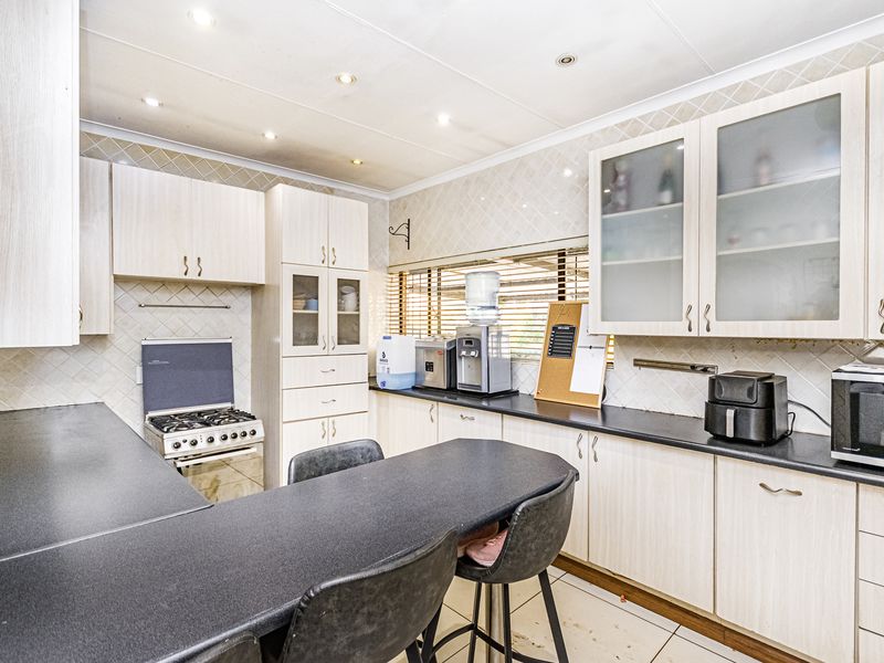 Functional kitchen featuring light-toned built-in cabinetry, dark laminate countertops, a gas stove, tiled backsplash, and a convenient breakfast bar area.