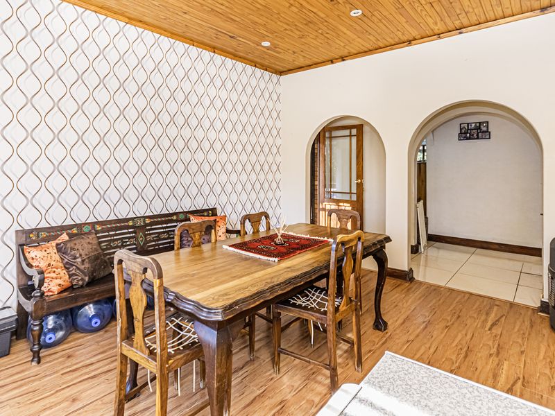 Dining room featuring timber ceiling, laminate flooring, and arched doorways leading to adjacent living spaces.